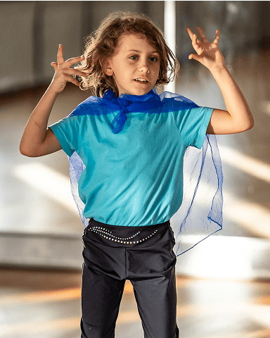 Kind mit blauem Tuch als Umhang beim Spielen in heller Innenraumumgebung