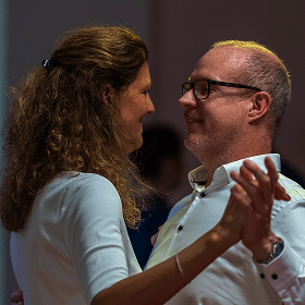 Paar tanzt eng umschlungen auf einer Veranstaltung in Innenraum mit gedämpfter Beleuchtung